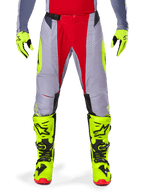 Alpinestars 2025 Techstar Melt Pants, Motocross Pants, Bright Red and Gray with fluorescent yellow accents, worn with matching neon yellow gloves and boots, featuring a magnetic waist buckle and laser-cut perforations for ventilation.