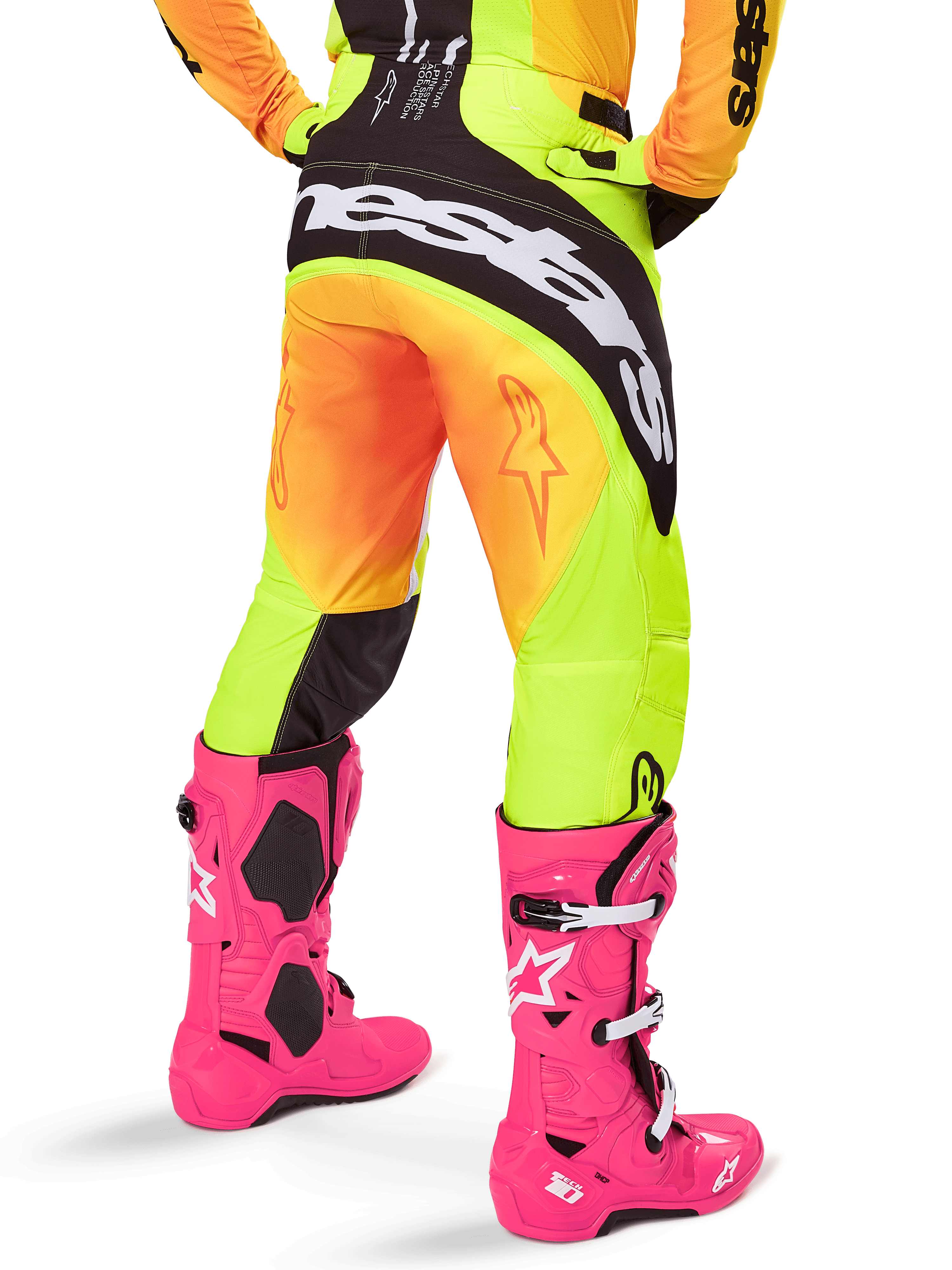 Rückansicht eines Motocross-Fahrers in der Alpinestars 2025 Techstar Melt Hose, gelb-orangefarbener Farbverlauf mit schwarz-weißem Branding am Gesäß, kombiniert mit leuchtend pinken Motocross-Stiefeln, Performance-Offroad-Ausrüstung.