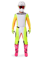 Motocross-Fahrer im Alpinestars 2025 Techstar Melt Gear Set, weißes Trikot mit gelben und orangefarbenen Ärmeln, neongelbe Hose mit weißen und orangefarbenen Akzenten, weißer Helm mit roter Brille, leuchtend pinke Stiefel und neongelbe Handschuhe, komplette Rennausrüstung für den Offroad-Wettbewerb