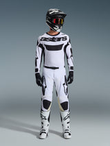 Motocross rider wearing Alpinestars 2026 Racer Riway Pants in White and Black, styled with a matching white jersey, black helmet with red goggles, black gloves, and white boots, featuring bold black Astars branding and a performance-driven design for off-road use.