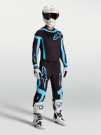 Alpinestars Supertech Vesta Hose, Motocross-Rennbekleidung für Herren in Schwarz und Türkis mit weißen Stiefeln und Helm.