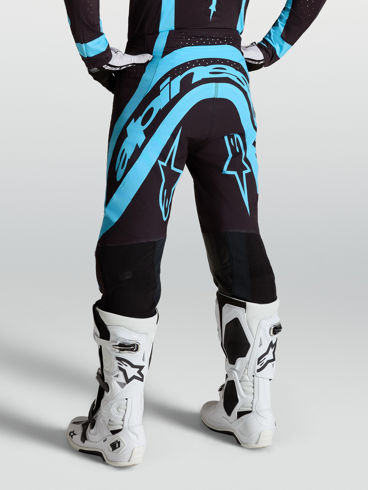 Alpinestars Supertech Vesta Pants, Black and Turquoise motocross gear, on-model rear view with white racing boots.