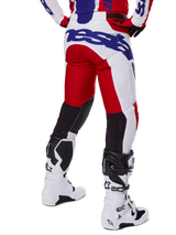 Alpinestars 2025 Racer Veil Hose, Motocross-Hose, Hellrot und Weiß mit blauem Branding, Rückansicht mit schwarzen Stretch-Belüftungseinsätzen an der Beinrückseite, kombiniert mit weißen Motocross-Stiefeln.