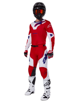 Alpinestars 2025 Racer Veil Hose, Motocross-Hose, Hellrot und Weiß, getragen als Teil einer kompletten Rennausrüstung mit passendem rot-weißen Trikot, schwarzem Helm mit oranger Brille, weißen Stiefeln und roten Handschuhen, mit auffälligen blauen Alpinestars-Logos.