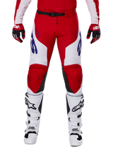 Alpinestars 2025 Racer Veil Hose, Motocross-Hose, Leuchtendes Rot und Weiß, getragen mit passenden roten Handschuhen und weißen Stiefeln, mit blauem Branding an den Oberschenkeln und einem schwarzen Taillengürtel, ergonomischer Sport-Schnitt für Performance-Fahren