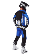 Motocross rider viewed from behind wearing Alpinestars 2025 Racer Veil Pants in Blue and Black, matching long-sleeve jersey with white branding, white and black Tech 7 boots, and a black SM10 helmet, full off-road racing gear set