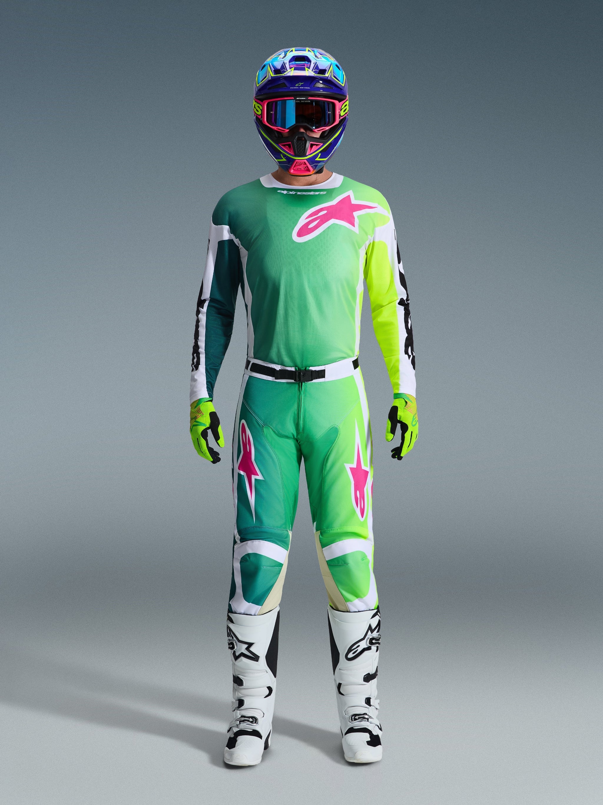 Alpinestars 2026 Racer Portl Hose, Motocross-Hose, Grün, Weiß und Schwarz mit pinkfarbenen Logo-Akzenten, getragen als Teil einer kompletten Rennausrüstung mit passendem Jersey, weißen Stiefeln und einem mehrfarbigen Helm, koordiniertes Outfit für professionellen Offroad-Rennsport.