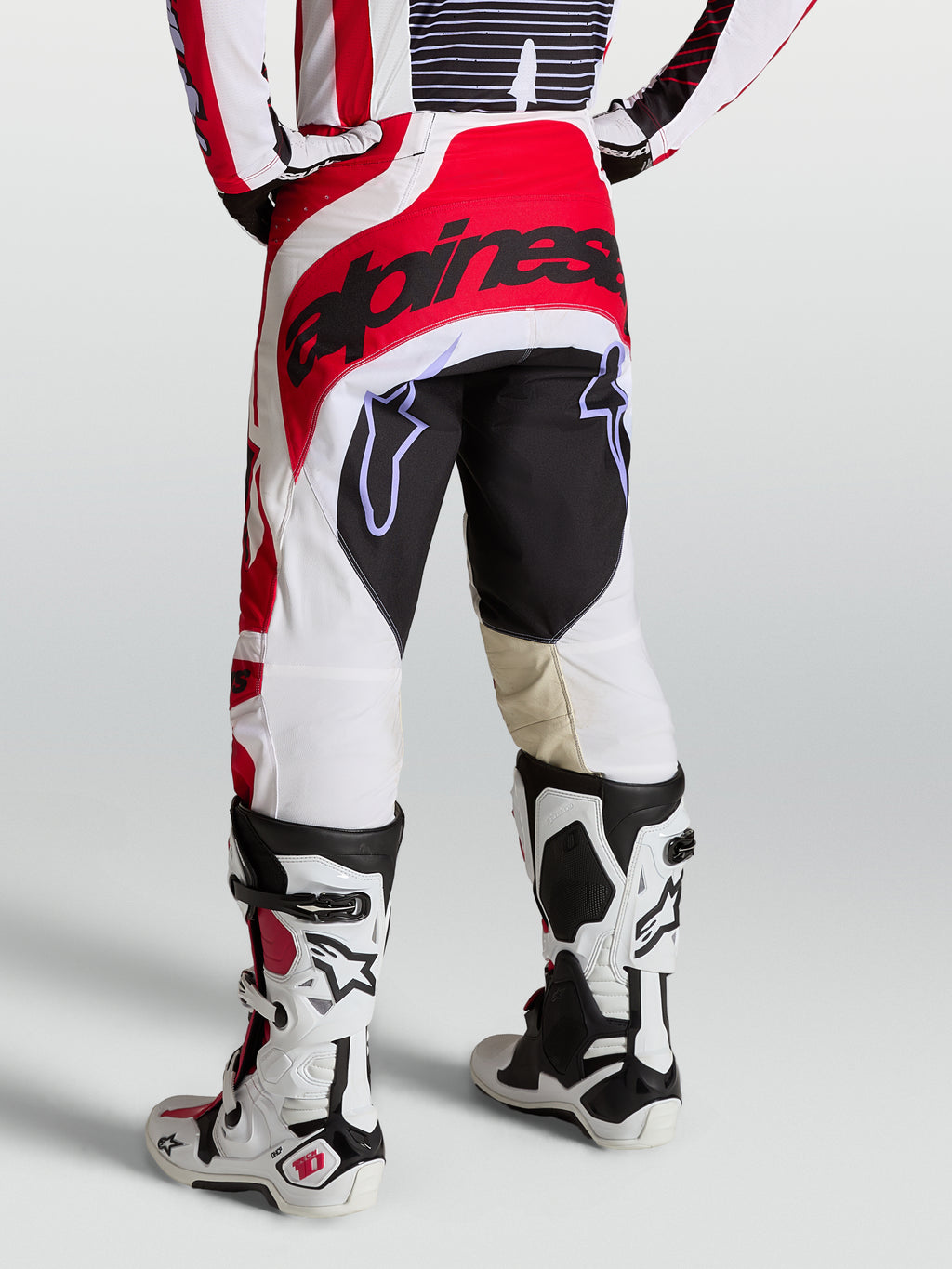 Alpinestars Techstar Maven Hose, Motocross-Hose für Herren, Rückansicht in Rot und Weiß, verstärkter Sitzbereich und athletische Rennpassform, getragen mit weißen Tech 10 Stiefeln.