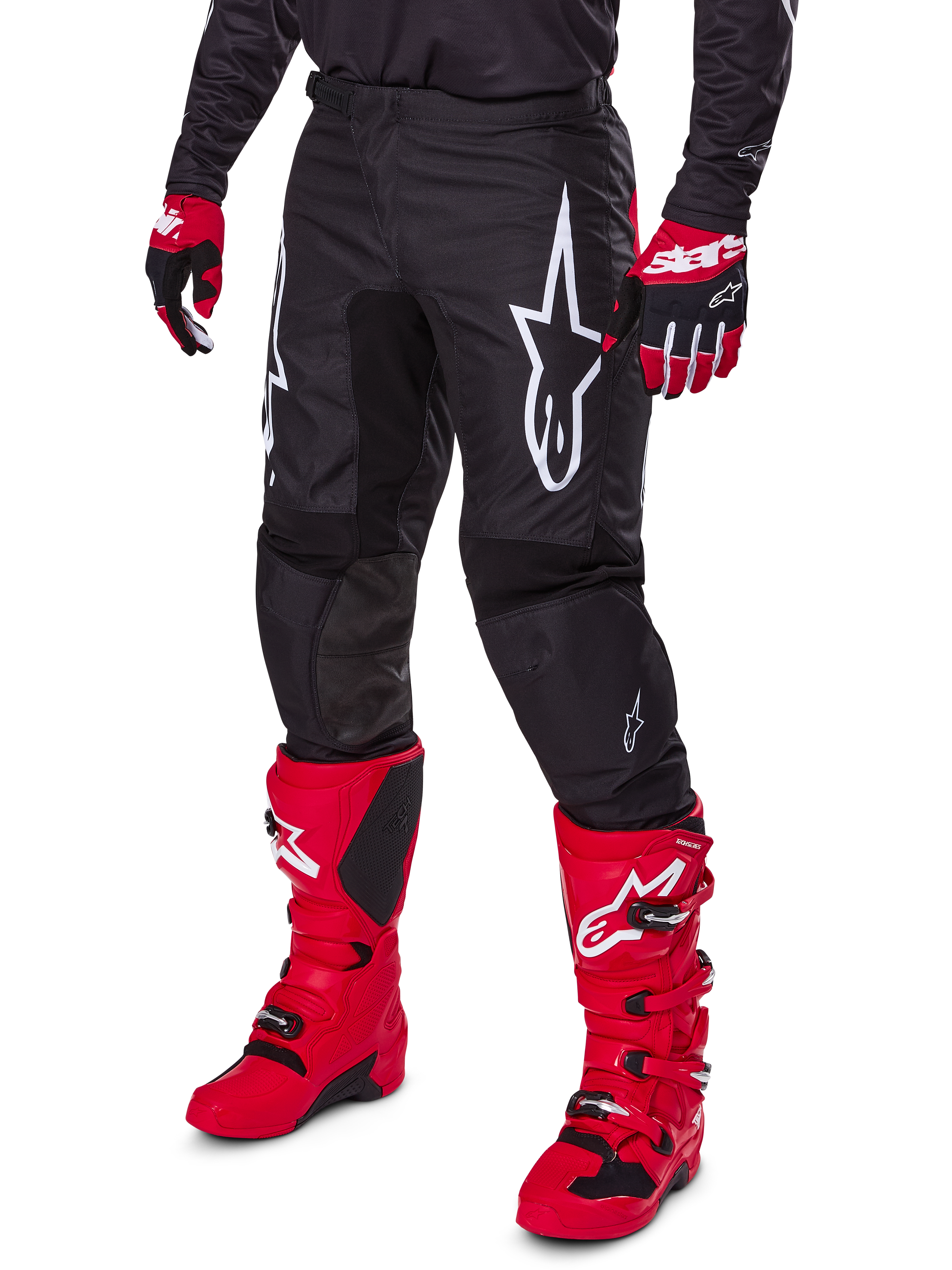 Alpinestars 2025 Fluid Haul Hose, Motocross-Hose, Schwarz, mit großem weißen Alpinestars-Logo, getragen mit leuchtend roten Stiefeln und rot-schwarzen Handschuhen, strapazierfähige 600D-Polygewebe-Konstruktion mit ergonomischem Schnitt für den Offroad-Rennsport