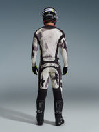 Motocross-Fahrer von hinten in der Alpinestars 2026 Racer Lahnd Hose in Sand Camo, passendes Langarm-Trikot mit grauem Camouflage-Muster, schwarze Motocross-Stiefel, schwarzer Helm und „astars“-Branding am Gesäß, entwickelt für professionellen Offroad-Rennsport.