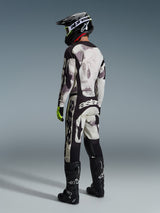 Motocross-Fahrer trägt die Alpinestars 2026 Racer Lahnd Hose in Sand Camo und Grau, komplettes Gear-Set mit passendem Jersey, schwarzem Helm und schwarzen Stiefeln, Rückansicht, die das markante Branding und das ergonomische Design hervorhebt.