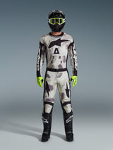 Motocross-Fahrer in kompletter Rennausrüstung, Alpinestars 2026 Racer Lahnd Hose und passendes Jersey in Sand Camo Grau, schwarzer Helm mit neongelber Brille, leuchtend neongelbe Handschuhe und schwarze Stiefel, abgestimmtes Profi-Outfit für den Offroad-Rennsport