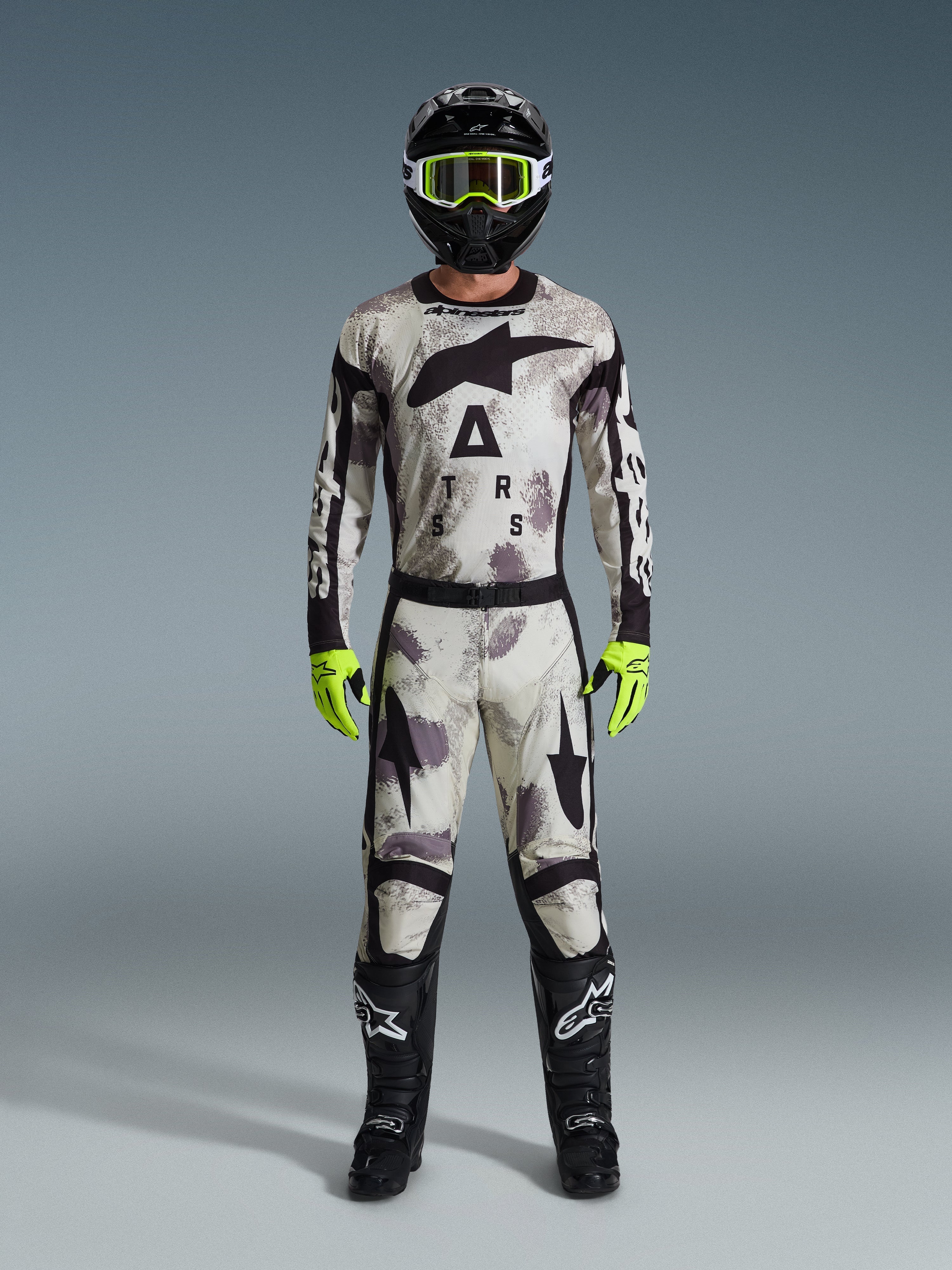 Motocross-Fahrer im 2026 Racer Lahnd Trikot und passender Hose in Sand Camo, schwarzer Helm mit neongelber Brille, neongelbe Handschuhe und schwarze Stiefel, komplettes Alpinestars Offroad-Rennausrüstungsset