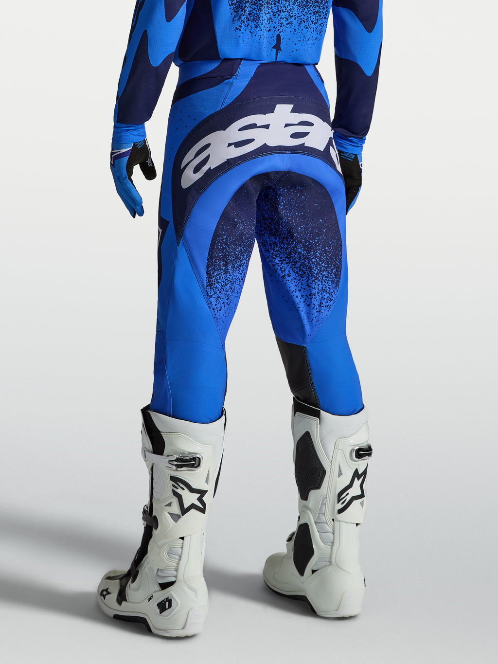 Alpinestars Techstar Swan Hose, Herren MX-Hose in Blau und Dunkelblau, weißes Astars-Sitzlogo und weiße Motorradstiefel.