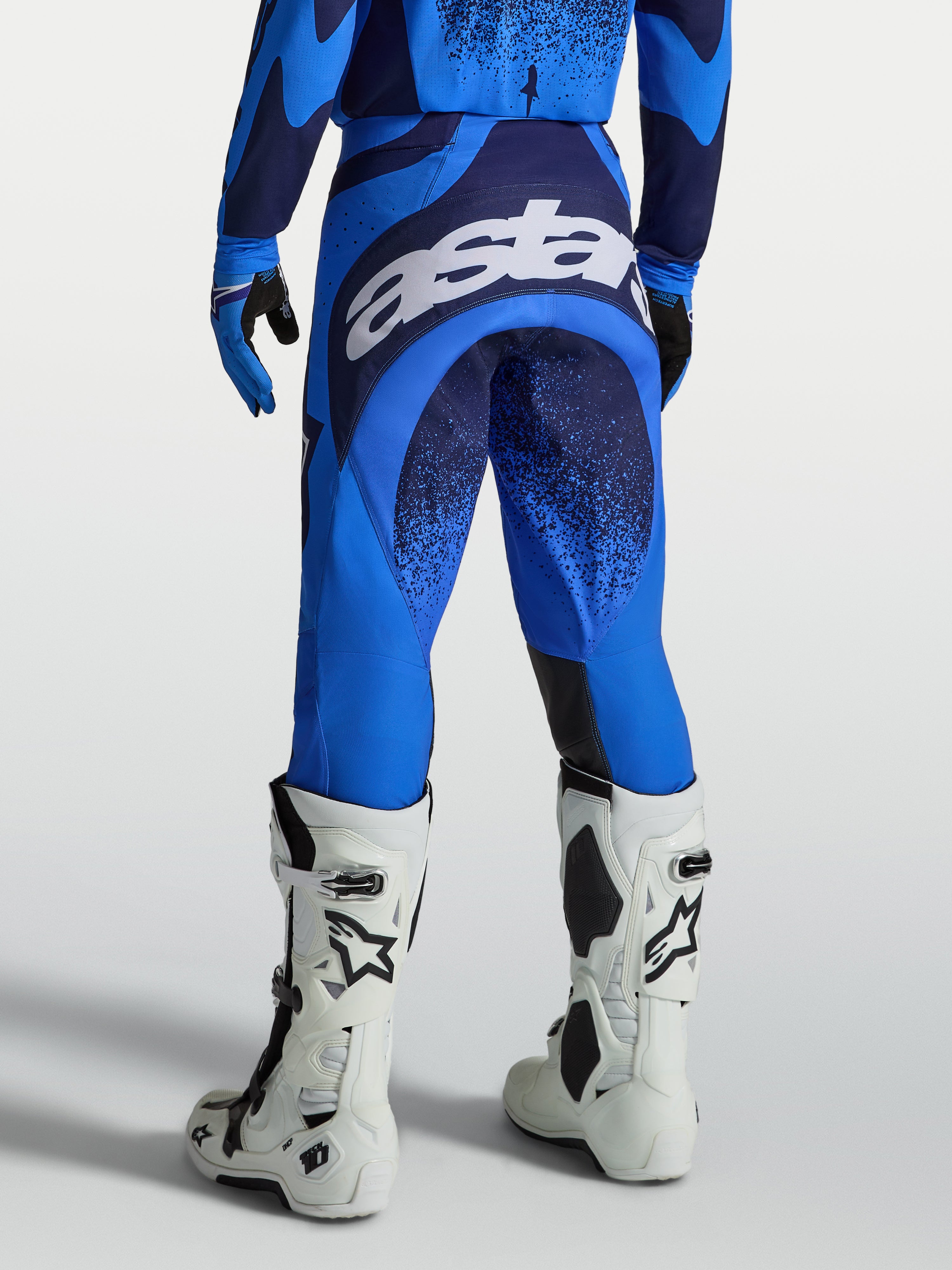 Alpinestars Techstar Swan Hose, Herren MX-Hose in Blau und Dunkelblau, weißes Astars-Sitzlogo und weiße Motorradstiefel.
