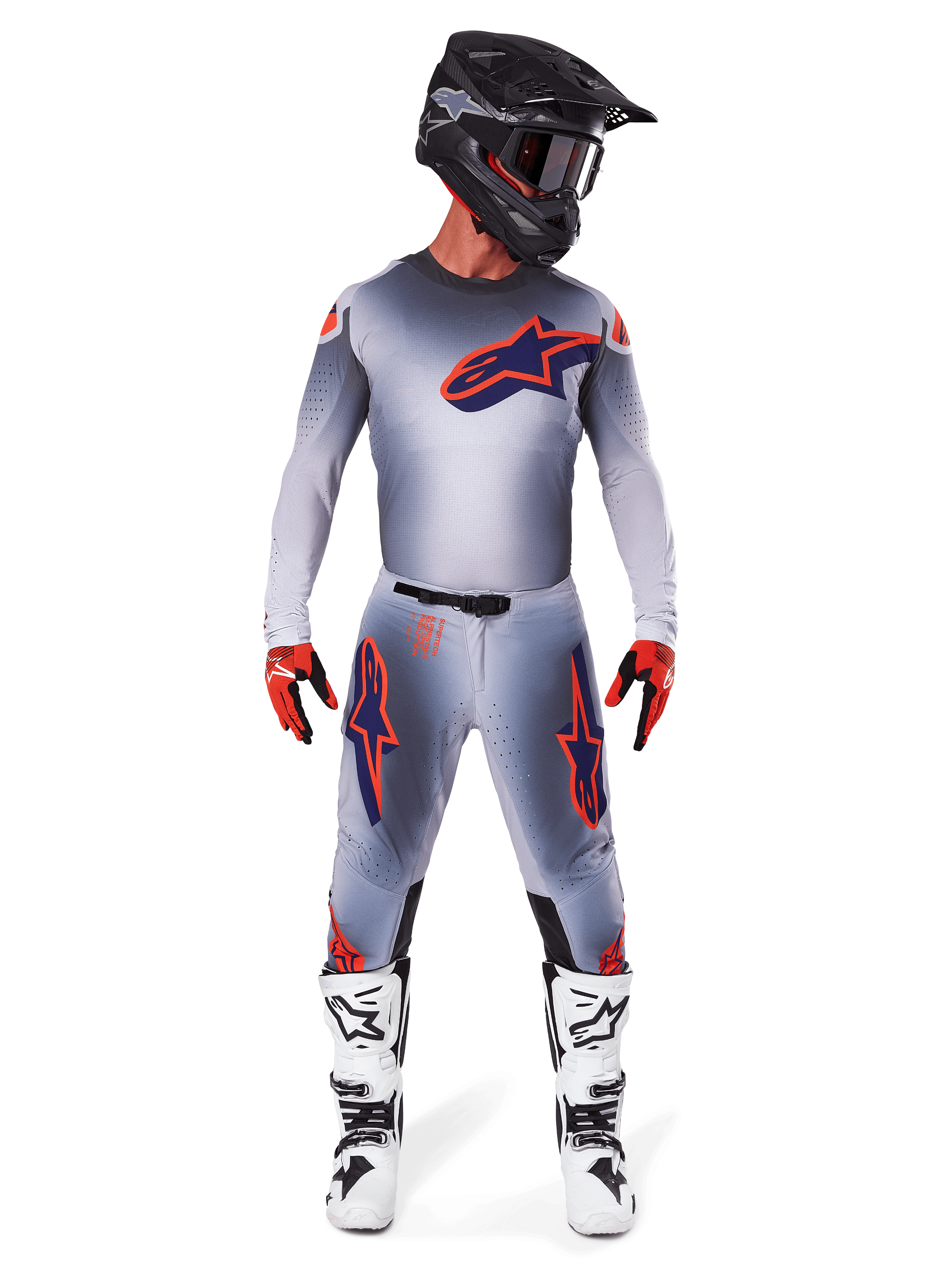 Motocross-Fahrer mit Alpinestars 2025 Supertech Lipan Hose und passendem Trikot in Gray Orange Fluo, markante orangefarbene und marineblaue Logos, kombiniert mit schwarzem Helm, roten Handschuhen und weiß-schwarzen Stiefeln, komplette Rennausrüstung für Offroad-Performance.