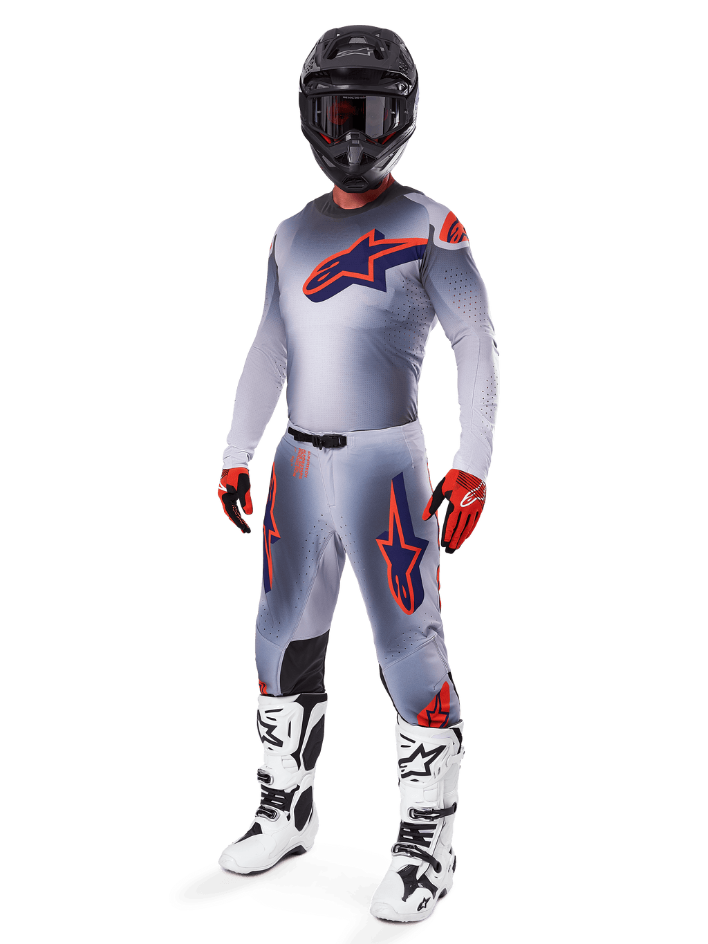 Motocross-Fahrer in kompletter Alpinestars 2025 Supertech Lipan Rennausrüstung, Grau und Orange Fluo, graues Trikot mit großem orangefarbenem Brustlogo, passende Hose mit orangefarbenen Akzenten, schwarzer Helm, rote Handschuhe und weiße Stiefel, professionelles Offroad-Rennoutfit