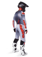 Alpinestars 2025 Supertech Lipan Hose in Grau und Orange Fluo, Motocross-Fahrer in der Rückansicht, passendes langärmliges Trikot, schwarzer Helm und weiß-schwarze Tech-Stiefel, komplette professionelle Offroad-Rennausrüstung