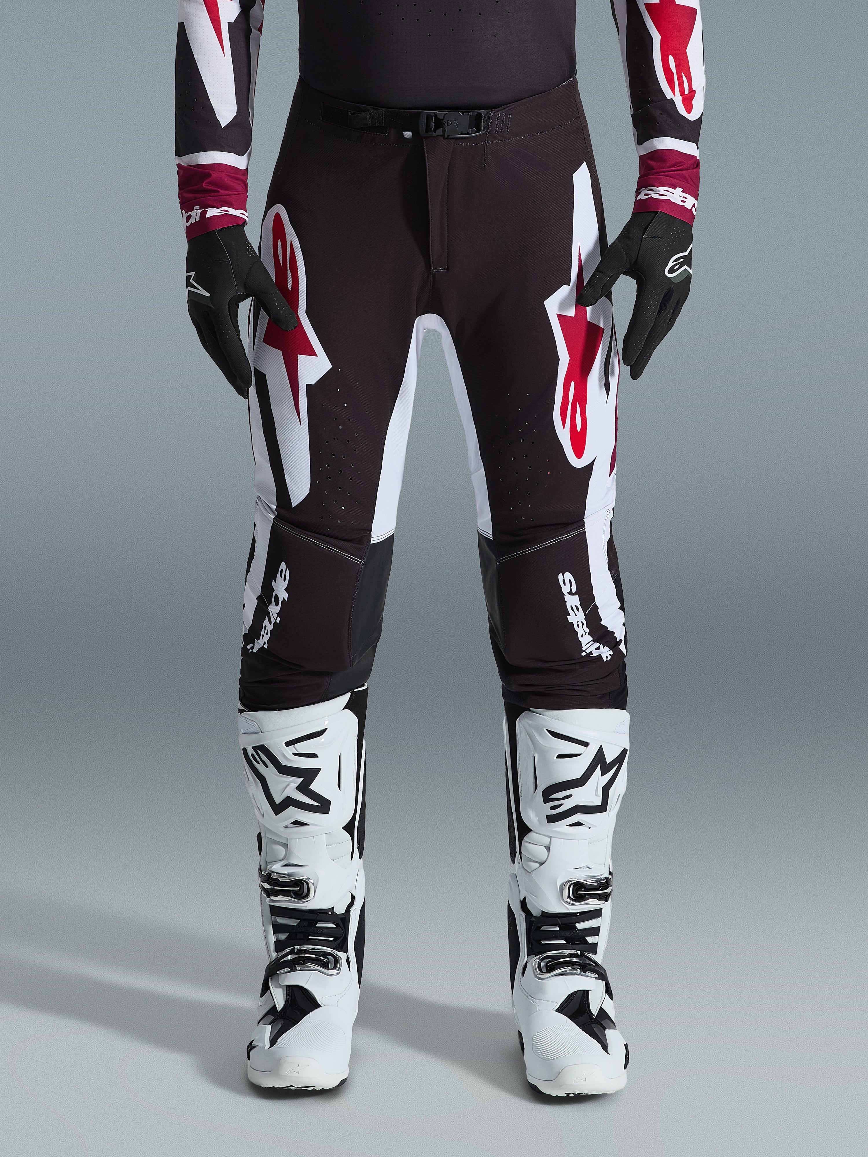 Alpinestars 2026 Supertech AFD Vista Pants, Motocross Pants, Black Red and White, featuring large graphic logos on the thighs and knees, worn with white racing boots and black gloves, athletic race-ready design for elite off-road competition