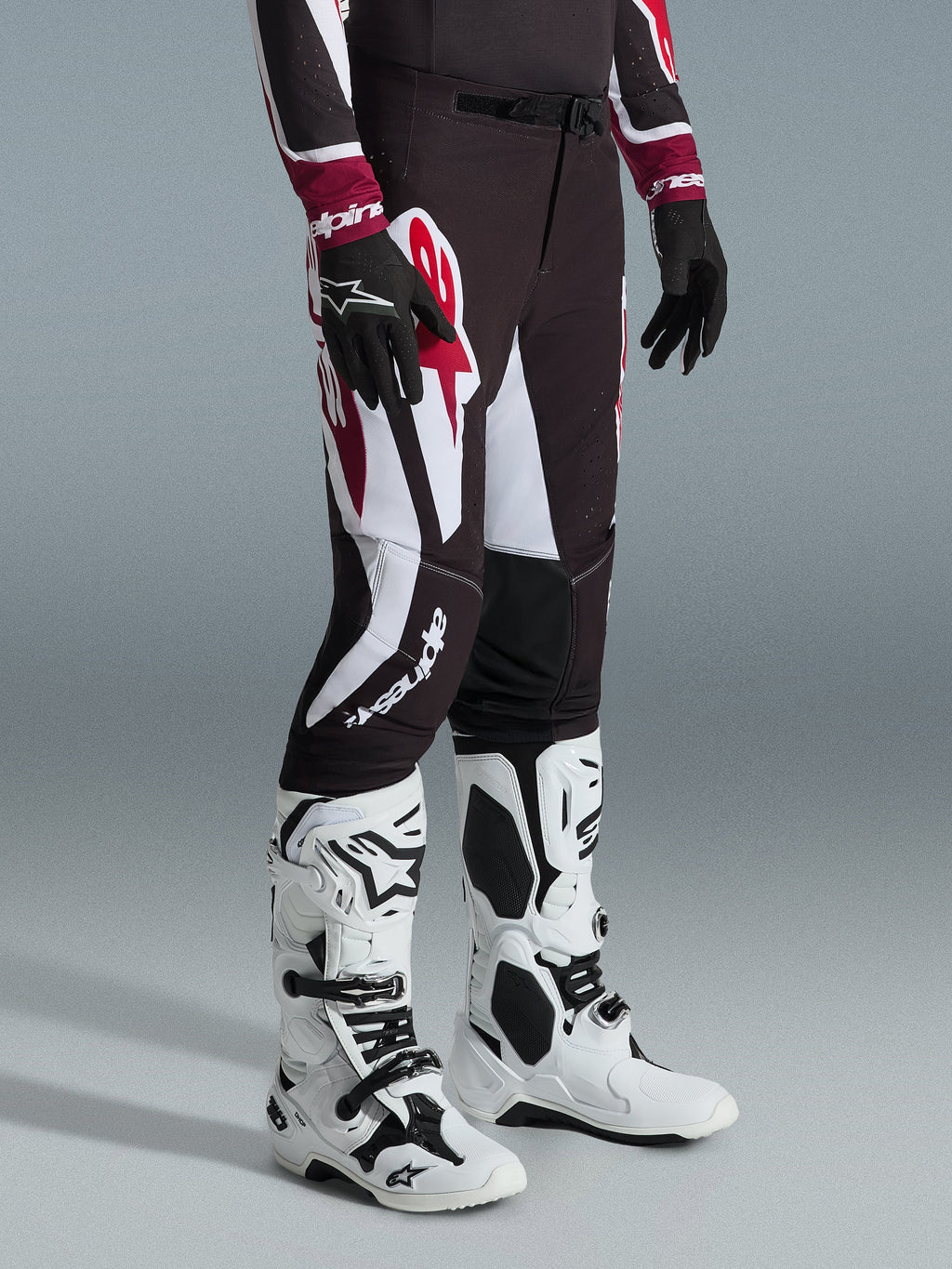 Alpinestars 2026 Supertech AFD Vista Hose, Motocross-Hose, Schwarz, Rot und Weiß, mit markanten grafischen Mustern und Branding, getragen mit weiß-schwarzen Offroad-Stiefeln und schwarzen Handschuhen, professionelle athletische Passform.