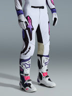 Alpinestars 2026 Supertech AFD Vista Hose, Motocross-Hose, Weiß, Lila und Schwarz, mit einem Astar-Logo mit pinkfarbenem und lila Farbverlauf, getragen mit passenden weiß-lila Motocross-Stiefeln und Handschuhen, athletische Rennpassform mit hellbraunen Leder-Innenknie-Paneelen und perforierten Details.