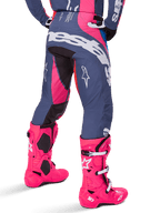 Alpinestars 2025 Techstar Dreem Hose, Motocross-Hose, Grau und leuchtendes Pink, getragen mit passenden pinkfarbenen Stiefeln, mit großem weißem Alpinestars-Branding am Gesäß und Stern-Logos an den Beinen, strapazierfähige athletische Passform für Offroad-Performance
