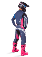 Alpinestars 2025 Techstar Dreem Hose, Motocross-Fahrer von hinten, graublaues und magentafarbenes Design mit schwarzen Akzenten, getragen mit passendem Trikot und leuchtend pinken Stiefeln, athletische Rennpassform für Offroad-Performance.