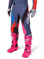 Alpinestars 2025 Techstar Dreem Hose, Motocross-Hose, Dunkelgrau mit blauen, roten und pinken Panels, weiße Grafiken, getragen mit leuchtend pinken Stiefeln und schwarz-weißen Handschuhen, auffälliges High-Visibility-Design