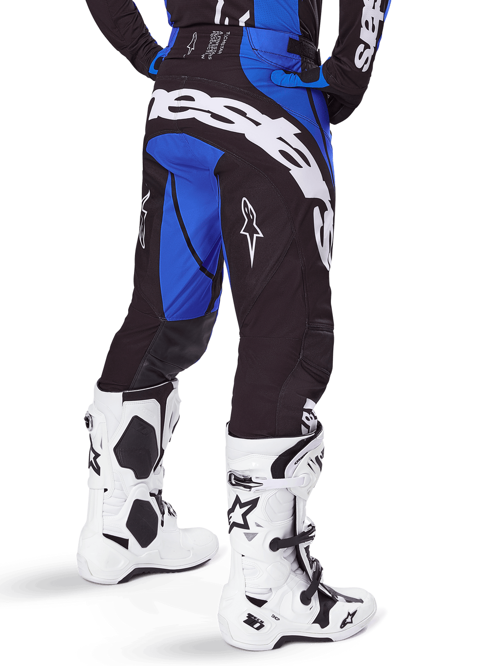 Alpinestars 2025 Techstar Dreem Hose, Motocross-Hose, Schwarz und Blau, Rückansicht mit markantem weißem Alpinestars-Schriftzug am Gesäß, kombiniert mit weiß-schwarzen Motocross-Stiefeln und passendem blauem Jersey, athletische Passform für den Offroad-Rennsport
