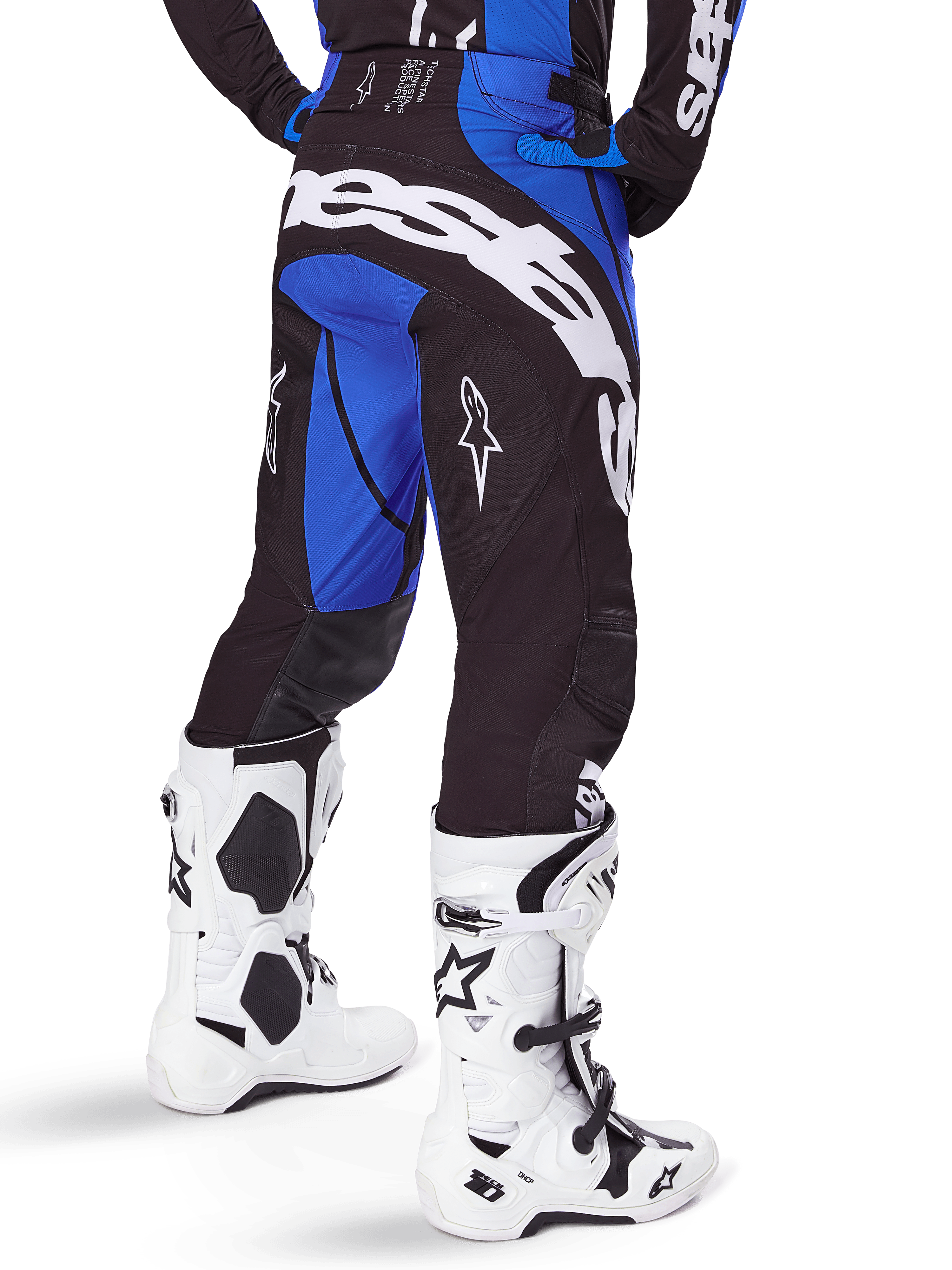 Alpinestars 2025 Techstar Dreem Hose, Motocross-Hose, Schwarz und Blau, Rückansicht mit markantem weißem Alpinestars-Schriftzug am Gesäß, kombiniert mit weiß-schwarzen Motocross-Stiefeln und passendem blauem Jersey, athletische Passform für den Offroad-Rennsport