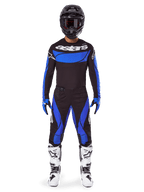 Motocross-Fahrer im Alpinestars 2025 Techstar Dreem Gear Set, schwarzes Jersey mit blauem Brustpanel und Ärmeln, passende schwarz-blaue Hose, schwarzer Helm mit Brille und weiße Stiefel, komplettes koordiniertes Motocross-Outfit für den Offroad-Rennsport.