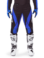 Alpinestars 2025 Techstar Dreem Hose, Motocross-Hose, Schwarz und Blau, getragen mit passendem Trikot, Handschuhen und weißen Stiefeln, mit blauen Seiteneinsätzen und athletischer Race-Passform, strapazierfähiges Material für den Offroad-Rennsport