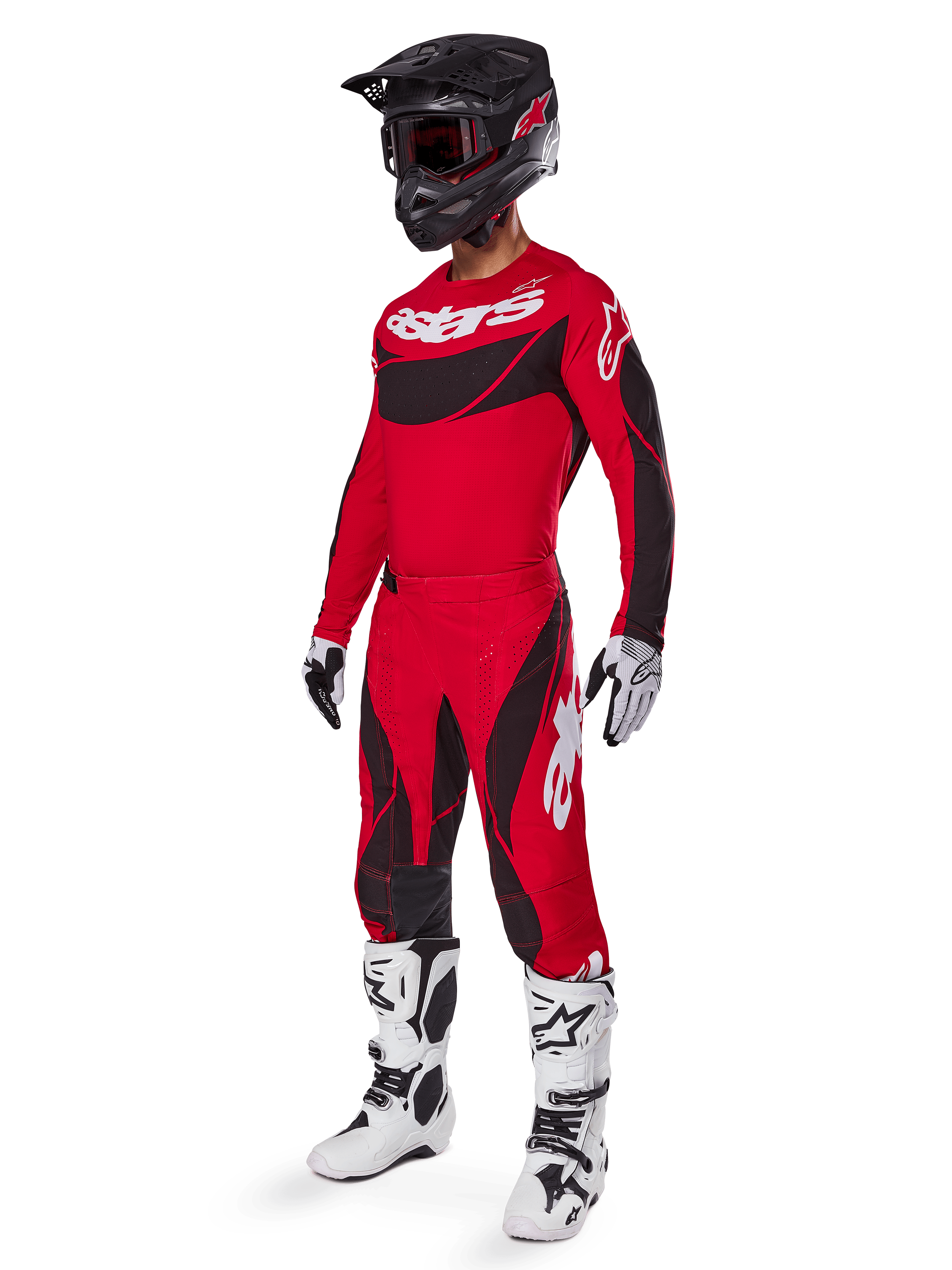 Motocross-Fahrer in kompletter Rennausrüstung mit Alpinestars 2025 Techstar Dreem Hose in Hellrot und Schwarz, passendes rot-schwarzes Trikot mit weißem Logo, schwarzer Helm und weiß-schwarze Stiefel, abgestimmtes Outfit für Offroad-Rennen