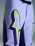 Alpinestars 2026 Supertech Scenz Hose, Motocross-Hose, Lila und Fluo-Gelb, Nahaufnahme mit großem gelben Logo auf dem Oberschenkel, lasergeschnittenen Perforationen zur Belüftung und magnetischem Bundverschluss, sportliche Offroad-Ausrüstung