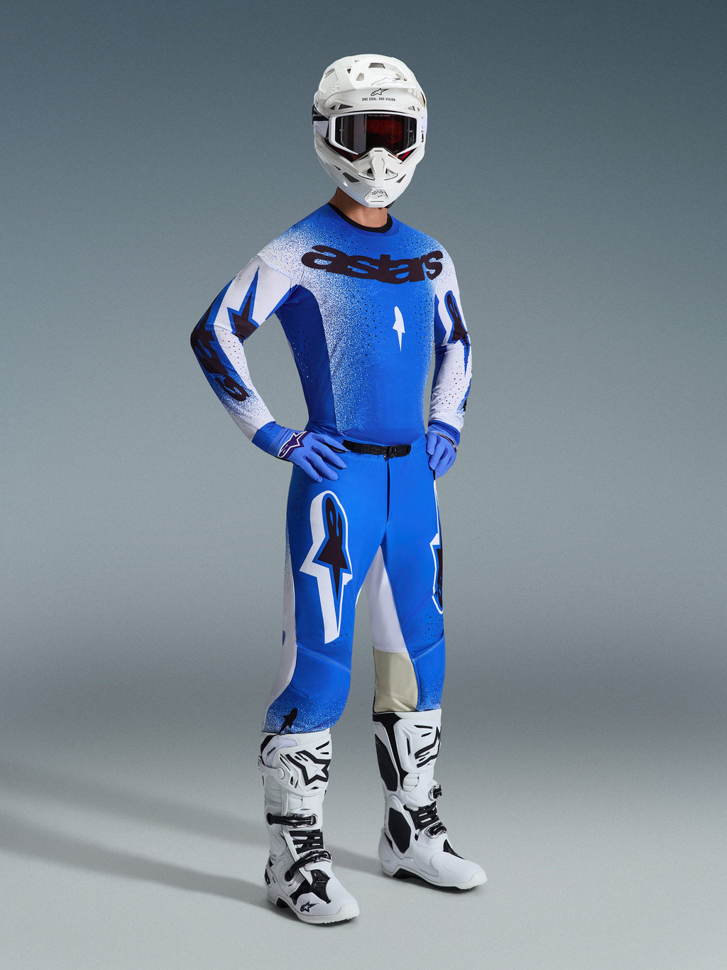 Motocross-Fahrer in kompletter Rennausrüstung, mit der 2026 Supertech Scenz Hose in UCLA Blau und Weiß, passendes blau-weißes Trikot mit Astars-Logo, weißer Helm mit roter Brille sowie weiße und schwarze Stiefel, abgestimmtes Outfit für professionellen Offroad-Rennsport.