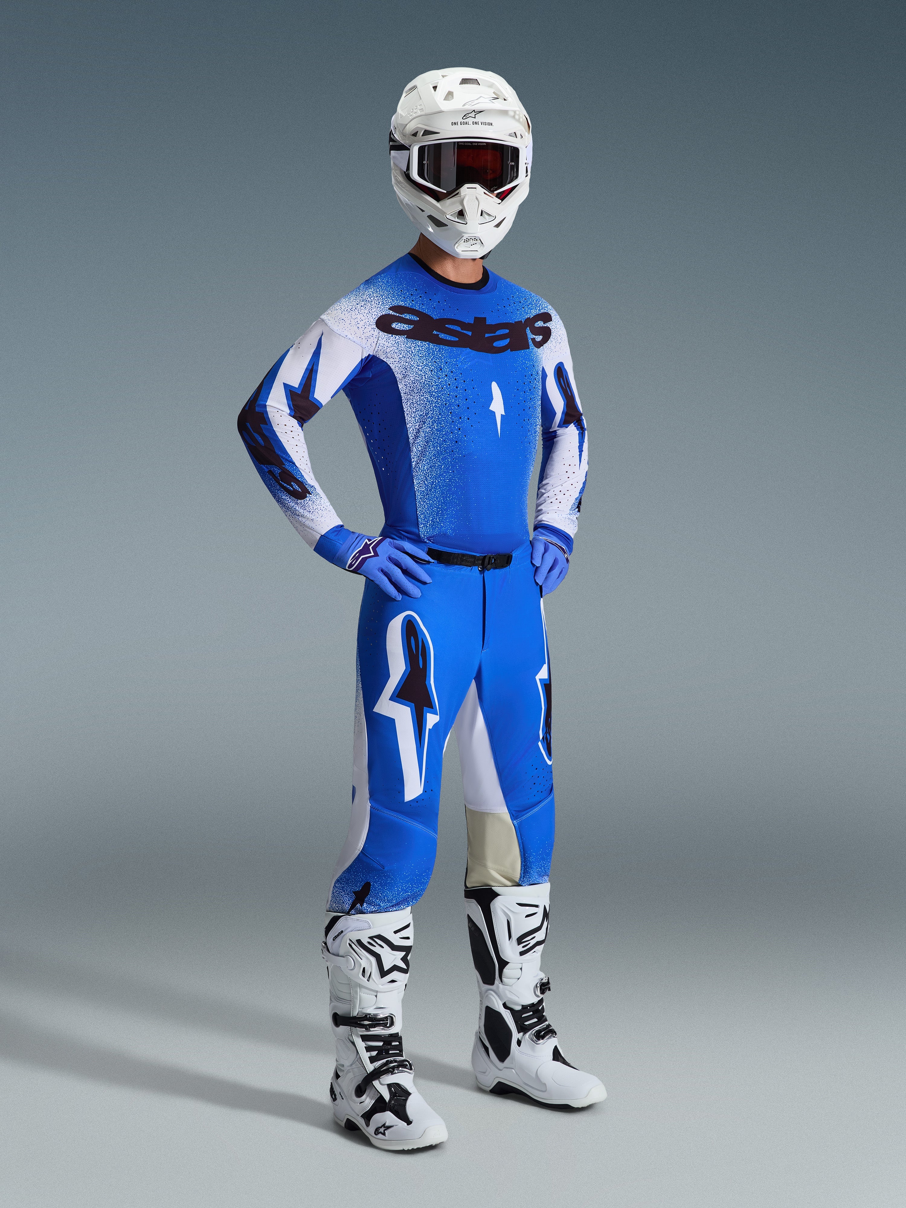 Motocross-Fahrer in kompletter Rennausrüstung, mit der 2026 Supertech Scenz Hose in UCLA Blau und Weiß, passendes blau-weißes Trikot mit Astars-Logo, weißer Helm mit roter Brille sowie weiße und schwarze Stiefel, abgestimmtes Outfit für professionellen Offroad-Rennsport.