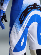 Alpinestars 2026 Supertech Scenz Hose, Motocross-Hose, UCLA Blau und Weiß, Nahaufnahme der Seite und Rückseite mit großem schwarzem A-Star-Logo und „SUPERTECH“-Branding, perforierte Belüftungszonen und strapazierfähiges Stretch-Gewebe.