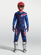 Alpinestars Racer Hunt Hose, Herren Motocross-Hose in Blau und Rot, strapazierfähige 600D-Polygewebe-Konstruktion, getragen von einem Model mit passender MX-Ausrüstung.