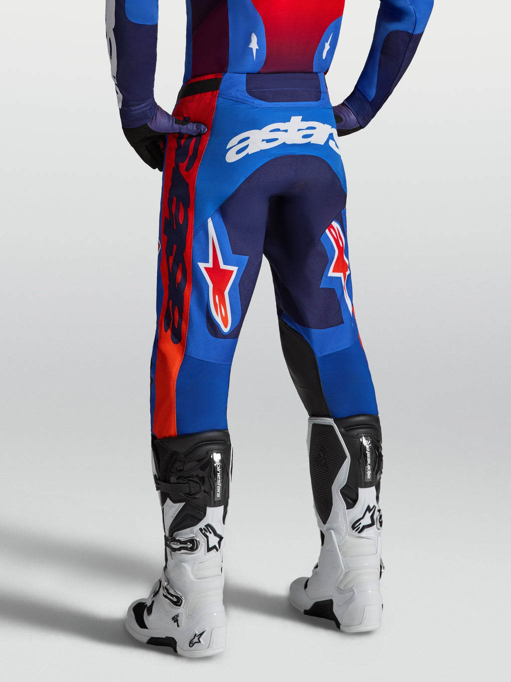 Alpinestars Racer Hunt Hose, Motocross-Hose in Blau und Rot, Rückansicht am Model mit weißen Stiefeln, ergonomische Rennpassform.