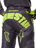 Alpinestars 2025 Racer Hollow Hose, Motocross-Hose, Dark Camo und Yellow Fluo, mit einem großen gelben Alpinestars-Logo auf der Rückseite, taktischem Camouflage-Muster mit leuchtend gelben Akzenten und strapazierfähiger Konstruktion für den Offroad-Rennsport.