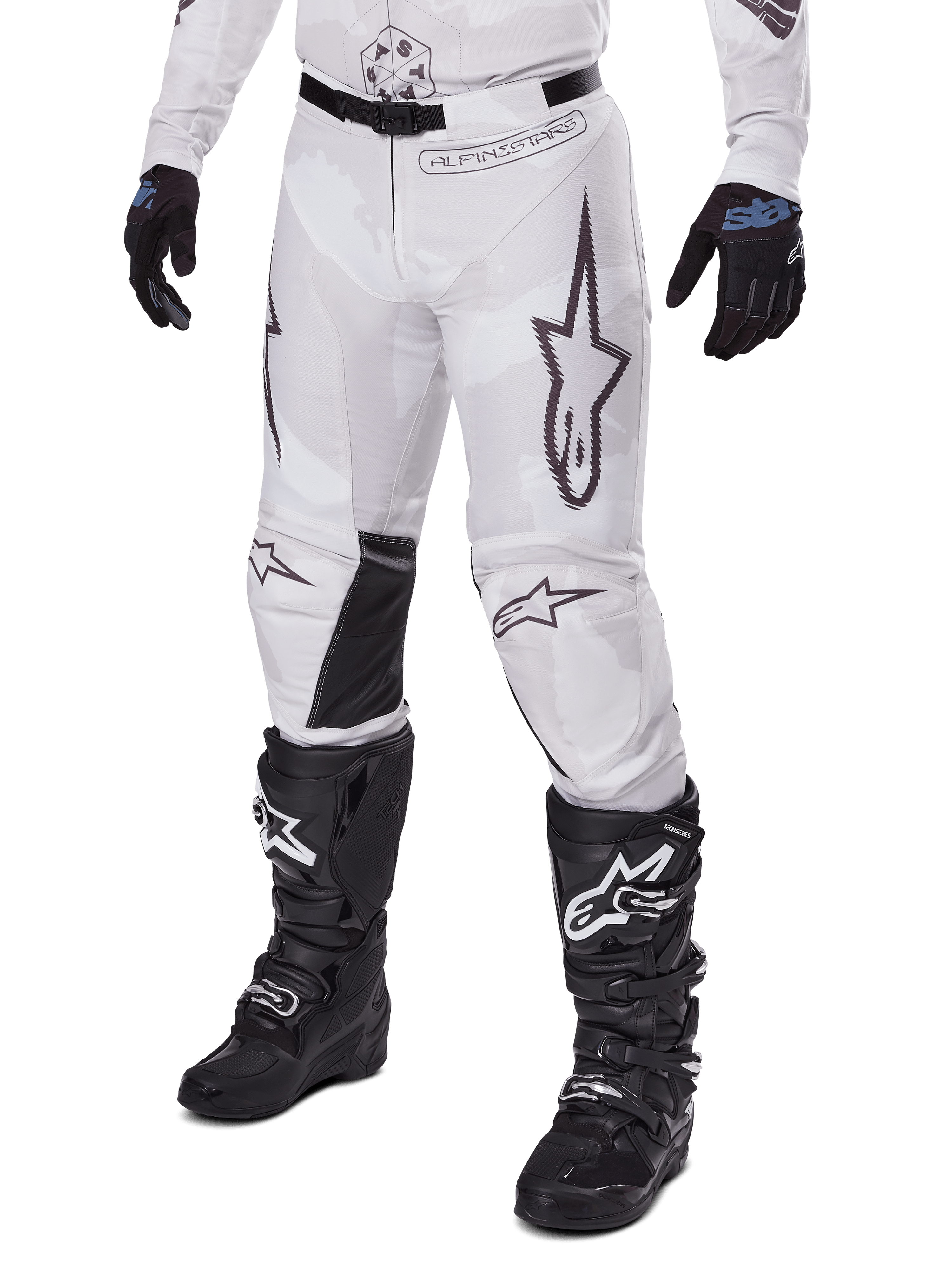 Alpinestars 2025 Racer Hollow Pants, Motocross Pants, White and Grey Camo, featuring large black outlined star logos and black leather inner knee panels, worn with black motocross boots and gloves, durable design for off-road racing.