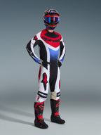 Alpinestars 2026 Techstar Knif Hose, Motocross-Hose, Schwarz, Weiß und Rot, getragen von einem Fahrer in kompletter Rennausrüstung mit passendem Jersey und Stiefeln, mit markanten roten Alpinestars-Logos auf weißen Einsätzen und einer leistungsorientierten sportlichen Passform.