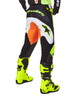 Alpinestars 2025 Fluid Wurx Hose, Motocross-Hose, Gelb und Schwarz mit orangefarbenen und weißen Akzenten, Rückansicht getragen mit passenden leuchtend gelben Stiefeln, strapazierfähige Konstruktion mit markantem Branding für das Dirtbike-Fahren