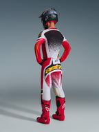 Motocross-Fahrer von hinten in kompletter Alpinestars Rennausrüstung, 2026 Techstar Nomur Hose in Rot, Weiß und Schwarz, passendes Trikot mit gesprenkeltem Design, leuchtend rote Stiefel, schwarzer Helm, markantes „astars“-Branding am Gesäß, koordiniertes Offroad-Rennoutfit
