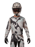 Alpinestars 2024 Racer Tactical Jersey, Motocross-Trikot, Iron Camo Dust Gray Tarnmuster, Fahrer mit passendem Helm und Schutzbrille sowie schwarzen Handschuhen, technische Ausrüstung für den Offroad-Rennsport