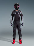 Alpinestars 2026 Fluid Apex Gear Set, Motocross Outfit, Black with Gray accents, jersey featuring large white Astars logo, matching pants with bold branding, black helmet with pink goggles, and bright red boots, complete off-road racing kit
