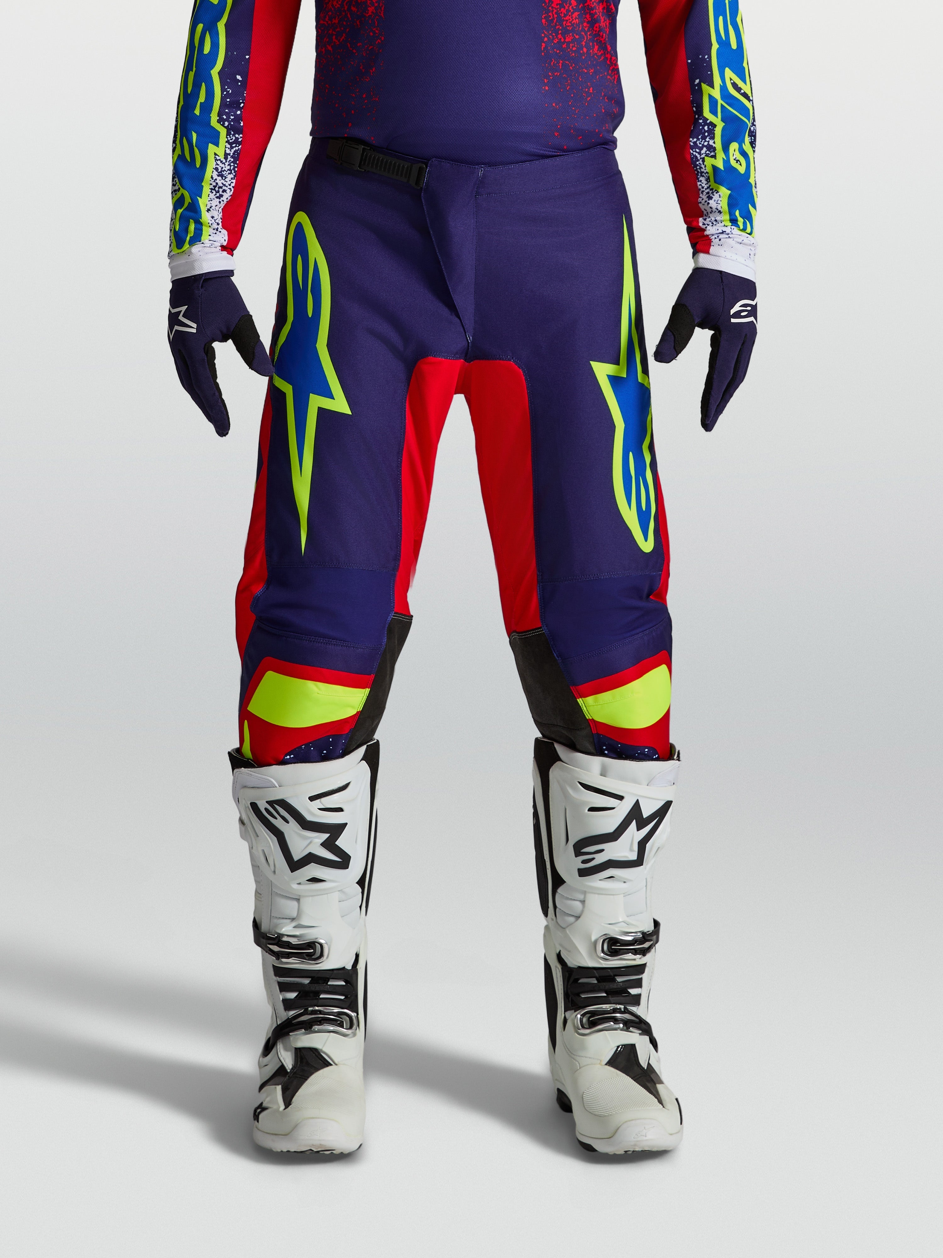Alpinestars Fluid Drag Hose, Herren-MX-Hose in Blau und Rot, sportliche Passform, am Model mit Motocross-Stiefeln gezeigt.