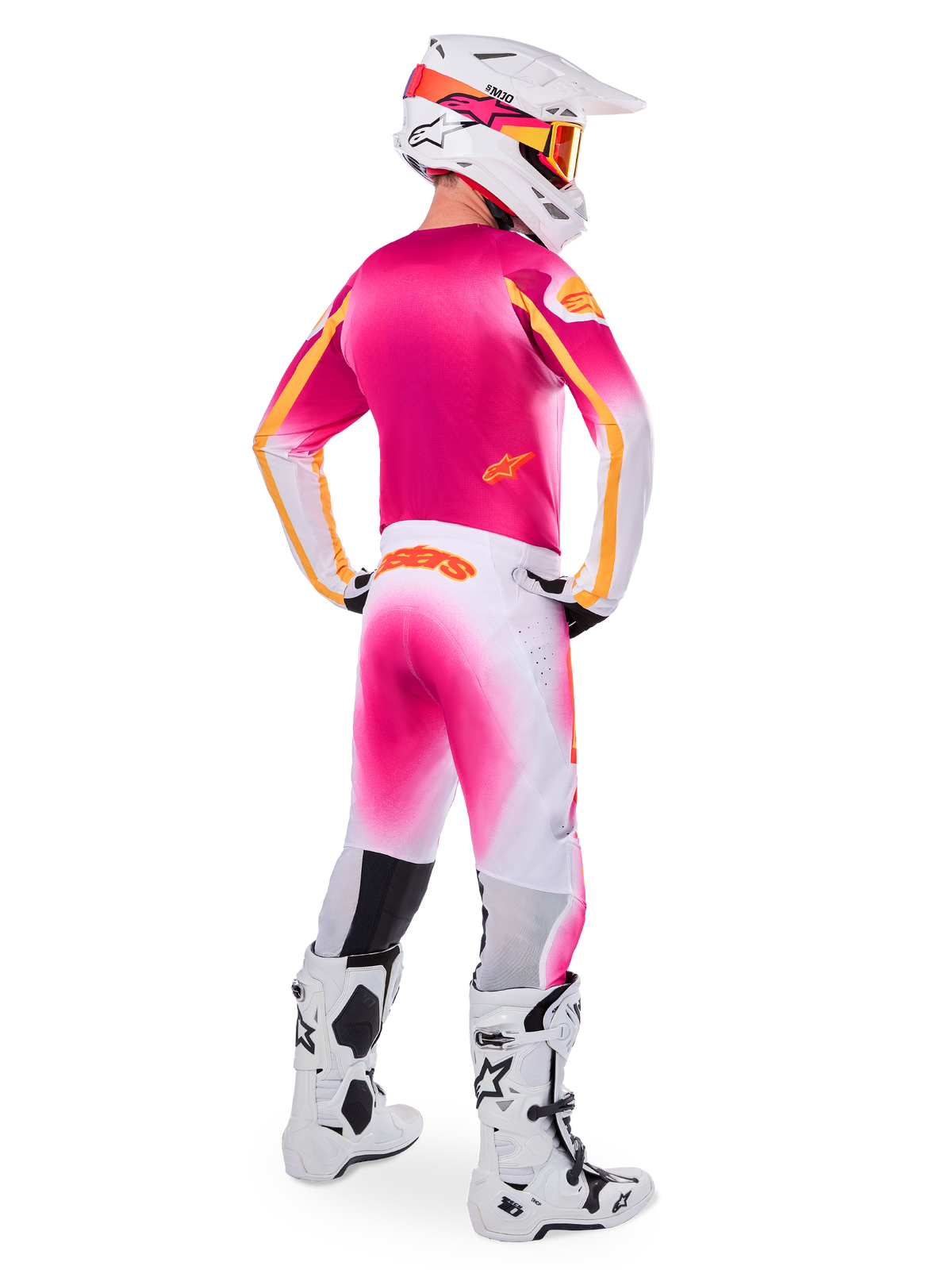 Motocross-Fahrer in der Rückansicht, Limited Edition Supertech AFD MIG Gear Set, pinkes Trikot mit orangefarbenen Akzenten, weiße Hose mit pinkem Farbverlauf und orangefarbenem Alpinestars-Branding, weißer Helm mit pinken Grafiken und orangefarbener Brille, weiß-schwarze Stiefel, professionelle Offroad-Rennausrüstung