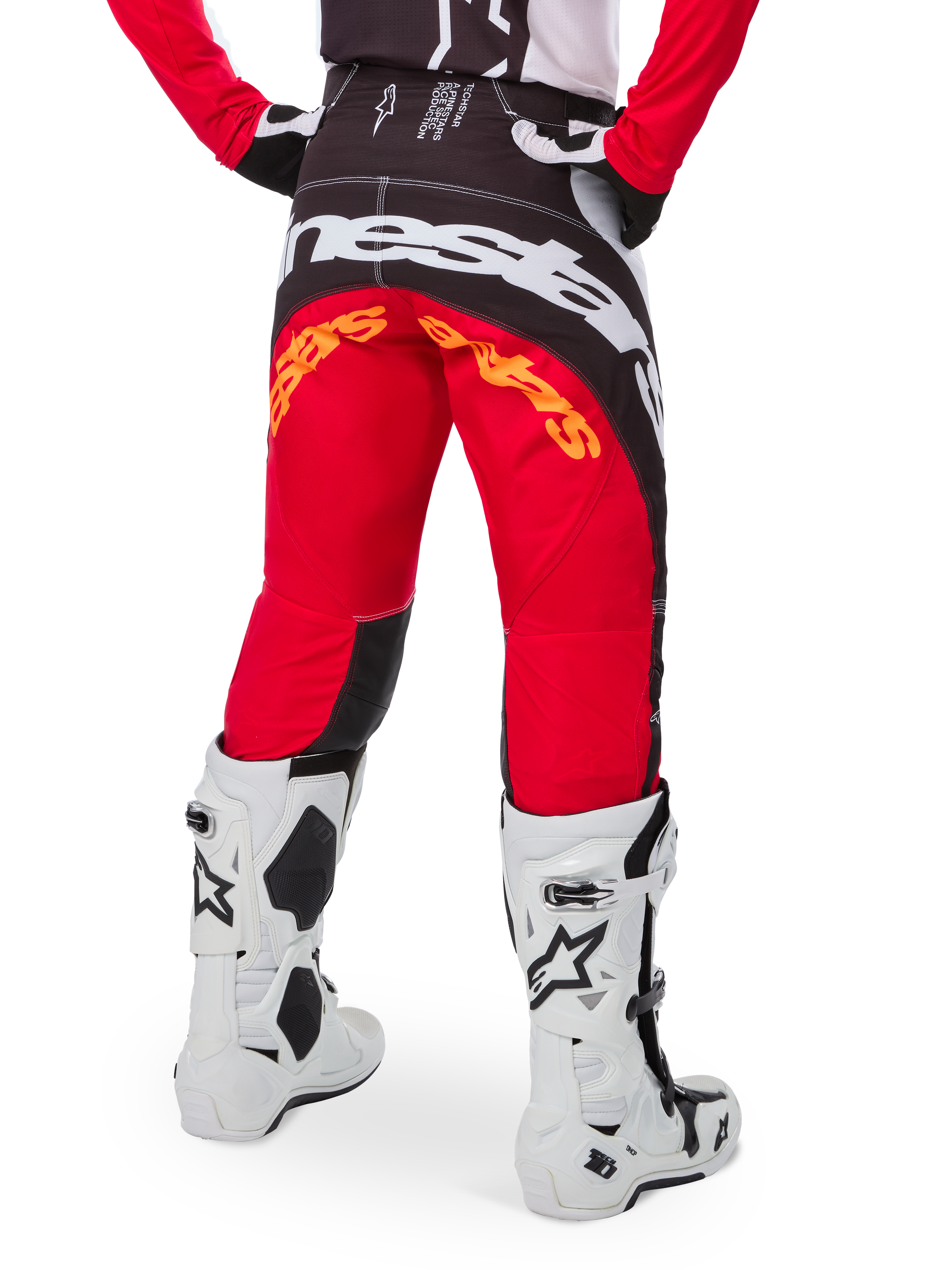 Alpinestars Limited Edition Techstar Deep Hose, Motocross-Hose, Schwarz, Weiß und High Red, Rückansicht mit markantem weißen Alpinestars-Logo auf dem Gesäß und orangefarbenem Branding, getragen mit weißen technischen Stiefeln für professionellen Offroad-Rennsport.