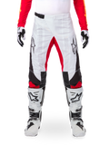 Alpinestars Limited Edition Techstar Deep Hose, Motocross-Hose, Schwarz, Weiß und High Red, getragen mit passendem rotem Jersey, weiß-schwarzen Handschuhen und Stiefeln, mit weißen Frontpanels, roten Akzenten an den Beininnenseiten, schwarzen Seitenpanels, Alpinestars-Logos auf den Oberschenkeln und laserperforierten Details zur Belüftung.